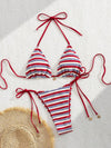 Striped bikini set with red, white, and blue colors on a textured surface.